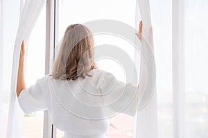 Pregnancy, motherhood, people and expectation concept - close up of happy pregnant woman opening window curtains