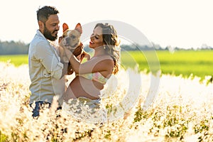 Pregnancy, motherhood, people and expectation concept, couple looking at dog on lap