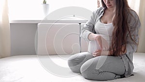 pregnancy, motherhood, people, expectation concept - happy pregnant woman touching her tummy in bed at home caring