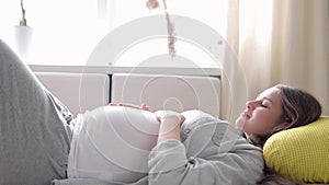 pregnancy, motherhood, people, expectation concept - happy tired pregnant woman touching her tummy resting lay on back