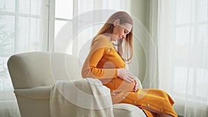 Pregnancy motherhood people expectation future. Pregnant woman with big belly sitting on chair near window at home. Girl