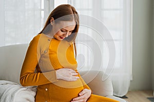 Pregnancy motherhood people expectation future. Pregnant woman with big belly sitting on chair near window at home. Girl