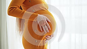 Pregnancy motherhood people expectation future. Pregnant woman hands touching big belly near window at home. Girl