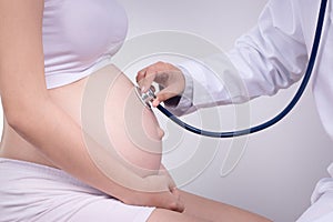 Pregnancy, motherhood, people, medicine and fertility concept - happy pregnant woman with doctor at maternity hospital. photo