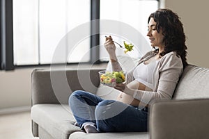 Pregnancy Nutrition. Young pregnant woman eating vegetable salad while relaxing at home
