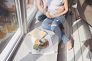 Pregnancy and people concept - happy man hugging his beautiful pregnant wife at home. Future parents waiting unborn baby.