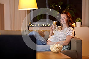 Happy smiling pregnant woman watching tv at home