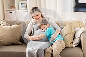 Happy pregnant mother and son hugging at home