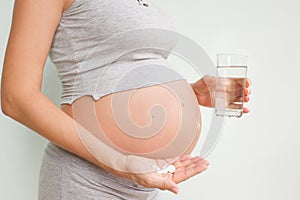 Pregnancy, people and health care concept - close up of pregnant woman. vitamins and minerals for pregnant women. Taking