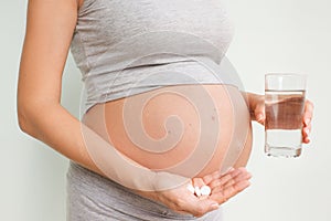 Pregnancy, people and health care concept - close up of pregnant woman. vitamins and minerals for pregnant women. Taking