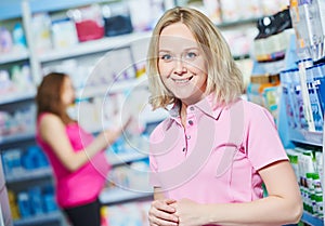 Pregnancy and pharmaceutics. pharmaceutist with pregnant on background at store