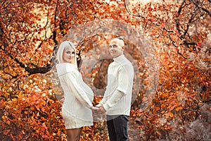 Pregnancy. Pregnant couple in white outfits enjoying in autumn forest park. Beautiful blond woman with husband. Parenthood