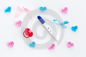 Pregnancy and preparation for childbirth. Babyshower. Pregnancy test near dummy and hearts white background top view