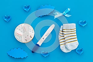 Pregnancy and preparation for childbirth. Babyshower. Pregnancy test near socks and hearts blue background top view