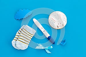 Pregnancy and preparation for childbirth. Babyshower. Pregnancy test near socks and hearts blue background top view