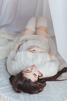 Pregnancy, rest, and expectation concept - close up of happy smiling pregnant woman lying in bed covered with canopy and