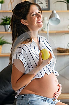 Pregnancy, rest, people and expectation concept. Happy pregnant woman touching her belly at home