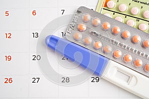 Pregnancy test and birth control pills on calendar, contraception