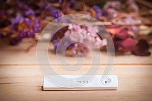 the pregnancy test and dried flowers on wooden background. proce