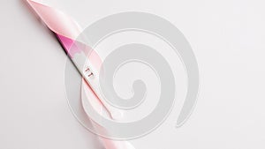 Pregnancy test kit. Positive woman pregnant test with pink silk ribbon on white background. New life and new family