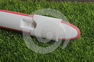 Pregnancy test pack positive result at green grass