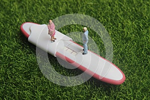 Pregnancy test pack positive result at green grass and family miniature figure