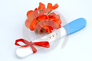 pregnancy test positive result with flower and present red ribbon
