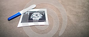 Pregnancy test stick and fetus ultrasound on the table