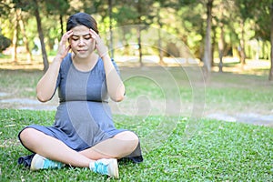 Pregnancy woman having headache and dizziness while her sitting in the park.