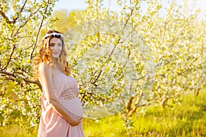 Pregnancy woman in the spring flowering garden. Beautiful pregnant girl