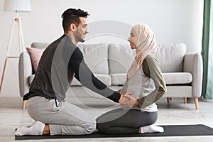 Pregnancy Workout. Happy Muslim Spouses Practicing Yoga Together At Home, Side View