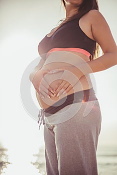 Pregnancy yoga and sea sunrise. Young pregnant woman with sport