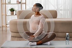 Pregnant african american woman exercising on yoga mat at home