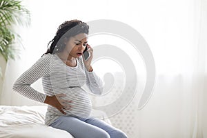 Pregnant African American Woman Feeling Pain In Belly, Calling Doctor On Cellphone