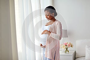 Pregnant african american woman at home window