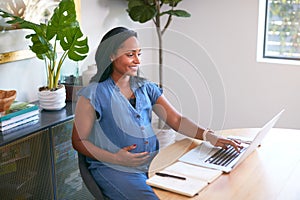 Pregnant African American Woman Using Laptop At Table Working From Home