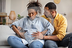 Pregnant African Woman Having Labor Pains, Husband Hugging Her Indoors