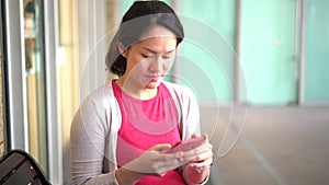 Pregnant Asian Chinese Mother using her smartphone to communicate worried