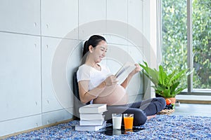 Pregnant asian moms Reading and drinking juice in the living room