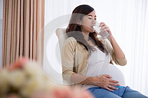 Pregnant asian woman drinking a glass of water