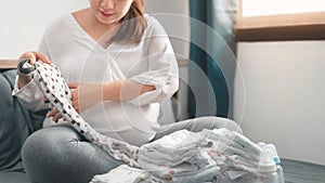 Pregnant asian woman prepare fold baby clothes for planning new born baby, Prepare before Give birth baby concept