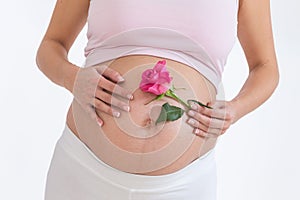 Pregnant asian woman with a rose in hands on her belly, isolated against white background