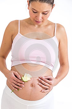 Pregnant asian woman with a rose in hands on her belly, isolated against white background