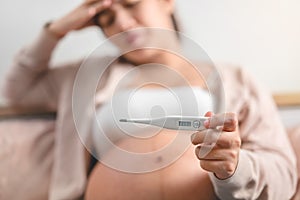 Pregnant asian woman used digital thermometer on bed at morning, Sick female with high fever, Selective focus, Healthy and