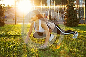 Pregnant, athletic girl on a street sports field is stretching
