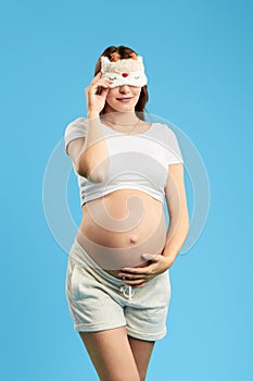 Pregnant attractive woman wearing sleeping mask on eyes