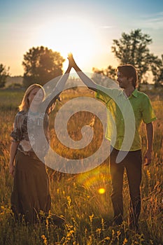 A pregnant beautiful woman with her husband on nature landscape smiling and touching her belly with love and care. Happy