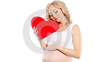 Pregnant beautiful woman holding red heart pillow in her hands isolated on white background