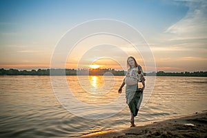 A pregnant beautiful woman on the river bank beach smiling with her mehandi ornament belly with love and care.