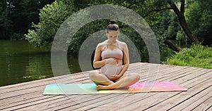 Pregnant beautiful woman yoga outdoors in the park in sunny summer day